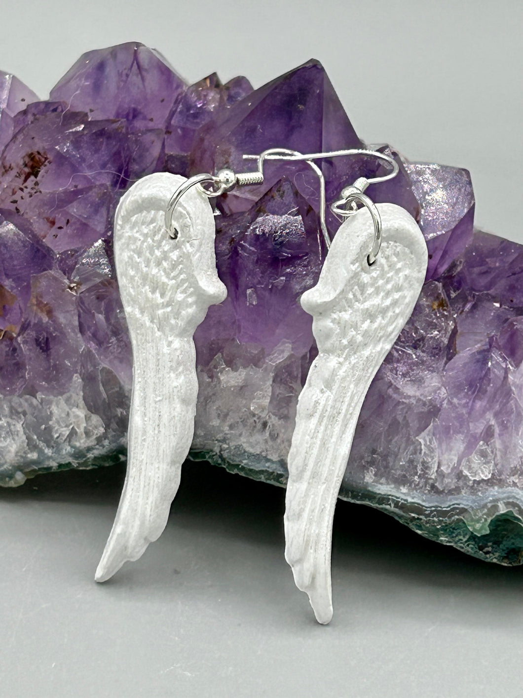 Shimmery white polymer clay earrings in the shape of angel wings are perfect for a subtle yet elegant look.