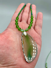 Load image into Gallery viewer, This Light Green Agate Geode Sliced Stone Chip Necklace is a statement piece for your jewelry collection. It features a bold green agate geode pendant surrounded by a glass bead necklace in varying shades of green. The silver leaf bail completes this chic, Boho-inspired necklace.  Measurements:   Necklace is 18” in length - pendant is 2 1/4” Height
