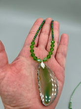 Load image into Gallery viewer, This Light Green Agate Geode Sliced Stone Chip Necklace is a statement piece for your jewelry collection. It features a bold green agate geode pendant surrounded by a glass bead necklace in varying shades of green. The silver leaf bail completes this chic, Boho-inspired necklace.  Measurements:   Necklace is 18” in length - pendant is 2 1/4” Height
