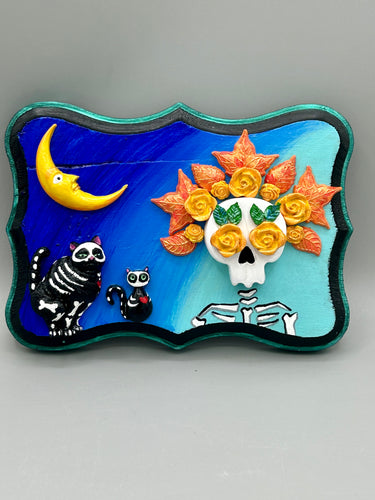 La Catrina y Gatita wall art is the purrfect hanging Day of the Dead art piece to add to your ofrenda. A tribute to an unbreakable bond and eternal love between cats and their guardians. Featuring a vibrant and intricate detail catrina and her floral crown accompanied by her beloved kitty cat. This Day of the Dead-inspired artwork adds a little touch of Mexican art to your home or office. A unique handcrafted gift for any cat lover. Measurements: H 5