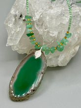 Load image into Gallery viewer, This Dark Green Agate Geode Sliced Stone Chip Necklace is a statement piece for your jewelry collection. It features a bold dark green agate geode pendant surrounded by a green aventurine, gold tone and green glass beaded necklace. The silver leaf bail completes this chic, Boho-inspired necklace.  Measurements:   Necklace is 19” in length - pendant is 2 1/4” Height
