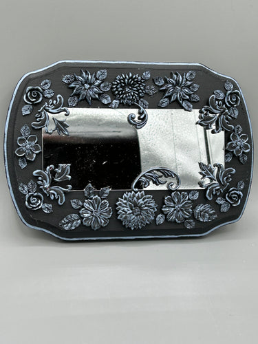 Make a bold statement with this handcrafted Goth Floral Decorative Mirror Wall Art Decor. The wood frame is complimented with highly detailed flowers, leaf and vine motifs, enhanced with shimmery metallic highlights for added texture and depth. Each intricate detail is carefully sculpted to create a unique and beautiful piece that's sure to make a statement.  H 6 3/4