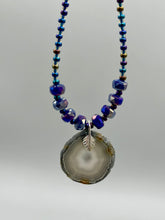 Load image into Gallery viewer, This Dark Gray-blue Agate Geode Sliced Stone Chip Necklace is a unique, eye-catching accessory to elevate your jewelry collection. The bold pendant features a striking gray-blue agate geode surrounded by eye-catching, shimmery dark-purple glass beads with beautiful iridescence that reflects hues of blue, pink, gold, and green. It&#39;s a perfect boho chic accent to update any look.   Measurements:   Necklace is 18” in length - pendant is 1 1/4” Height
