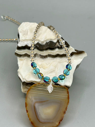 This Large Light Brown Banded Agate Geode Sliced Stone Chip Necklace is a must-have for any jewelry collection. Crafted with natural, banded geode and finished with a unique strand of bamboo, gold and clear beading, this piece adds a luxurious, earth-tone touch to any outfit. Pair it with casual or formal looks for a stunning, one-of-a-kind look.  Measurements:     Necklace is 18” in length - pendant is 2” Height 
