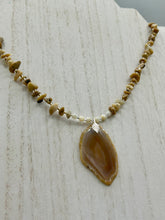 Load image into Gallery viewer, This Light Brown Banded Agate Geode Sliced Stone Chip Necklace is a luxurious addition to any jewelry collection. It features natural, light brown agate banded geode in a luxurious earth-tone. Suspended on a unique strand of natural bamboo chips and gold and clear beaded necklace. The combination of neutral colors and nature inspired design makes them the perfect accessory for any outfit.   Measurements:    Necklace is 18” in length - pendant is 2” Height
