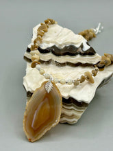 Load image into Gallery viewer, This Light Brown Banded Agate Geode Sliced Stone Chip Necklace is a luxurious addition to any jewelry collection. It features natural, light brown agate banded geode in a luxurious earth-tone. Suspended on a unique strand of natural bamboo chips and gold and clear beaded necklace. The combination of neutral colors and nature inspired design makes them the perfect accessory for any outfit.   Measurements:    Necklace is 18” in length - pendant is 2” Height
