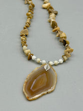 Load image into Gallery viewer, This Light Brown Banded Agate Geode Sliced Stone Chip Necklace is a luxurious addition to any jewelry collection. It features natural, light brown agate banded geode in a luxurious earth-tone. Suspended on a unique strand of natural bamboo chips and gold and clear beaded necklace. The combination of neutral colors and nature inspired design makes them the perfect accessory for any outfit.   Measurements:    Necklace is 18” in length - pendant is 2” Height
