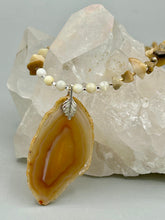 Load image into Gallery viewer, This Light Brown Banded Agate Geode Sliced Stone Chip Necklace is a luxurious addition to any jewelry collection. It features natural, light brown agate banded geode in a luxurious earth-tone. Suspended on a unique strand of natural bamboo chips and gold and clear beaded necklace. The combination of neutral colors and nature inspired design makes them the perfect accessory for any outfit.   Measurements:    Necklace is 18” in length - pendant is 2” Height
