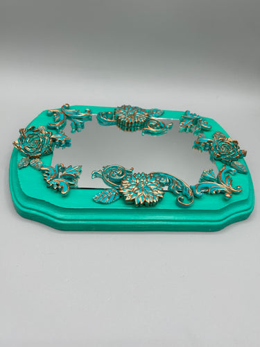 Make a bold statement with this handcrafted Turquoise And Patina Floral Decorative Mirror Wall Art Decor. The bright turquoise wood frame is complimented with highly detailed flowers, leaf and vine motifs, enhanced with shimmery patina color highlights for added texture and depth. Each intricate detail is carefully sculpted to create a unique and beautiful piece that's sure to make a statement. Comes ready to hang with a sawtooth hanger in the back. H 6 3/4