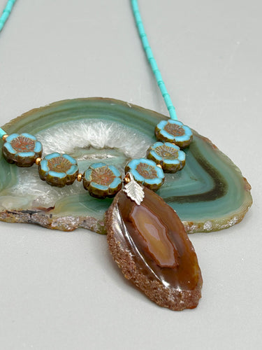 This exquisite Natural Dark Brown Agate Geode Sliced Stone Chip Necklace adds a unique touch of luxury to any look. Its banded geode and hibiscus flower glass beads offer a sophisticated bohemian style, and the natural gemstones are sure to make a statement. Add it to any outfit for a stylish and timeless touch. Measurements:     Necklace is 18” in length - pendant is 1 3/4” Height    Amber Stone Chip Earrings: 2