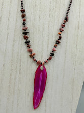 Load image into Gallery viewer, Unlock your inner goddess with this stunning Large Fuchsia Agate Geode Sliced Stone Chip Necklace. Featuring a vibrant fuchsia agate geode pendant surrounded by Rhodonite stone chips and gold and black glass beading, the silver leaf bail completes this chic and boho-inspired look. Make a bold statement with this bohemian-style gemstone necklace.   Measurements:    Necklace is 17 3/4” in length - pendant is 3” Height
