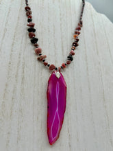 Load image into Gallery viewer, Unlock your inner goddess with this stunning Large Fuchsia Agate Geode Sliced Stone Chip Necklace. Featuring a vibrant fuchsia agate geode pendant surrounded by Rhodonite stone chips and gold and black glass beading, the silver leaf bail completes this chic and boho-inspired look. Make a bold statement with this bohemian-style gemstone necklace.   Measurements:    Necklace is 17 3/4” in length - pendant is 3” Height
