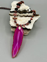 Load image into Gallery viewer, Unlock your inner goddess with this stunning Large Fuchsia Agate Geode Sliced Stone Chip Necklace. Featuring a vibrant fuchsia agate geode pendant surrounded by Rhodonite stone chips and gold and black glass beading, the silver leaf bail completes this chic and boho-inspired look. Make a bold statement with this bohemian-style gemstone necklace.   Measurements:    Necklace is 17 3/4” in length - pendant is 3” Height
