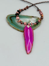 Load image into Gallery viewer, Unlock your inner goddess with this stunning Large Fuchsia Agate Geode Sliced Stone Chip Necklace. Featuring a vibrant fuchsia agate geode pendant surrounded by Rhodonite stone chips and gold and black glass beading, the silver leaf bail completes this chic and boho-inspired look. Make a bold statement with this bohemian-style gemstone necklace.   Measurements:    Necklace is 17 3/4” in length - pendant is 3” Height

