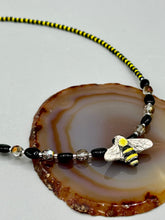 Load image into Gallery viewer, This beautiful Bee Pendant With Black and Yellow Beaded Necklace is the perfect accessory for any summer outfit. The vibrant colors will make a bold statement, while the black and gold blend adds a subtle elegance. Its perfect for any nature lover, hippie, or witchy style.  Measurements:  Necklace is 18”
