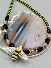 Load image into Gallery viewer, This beautiful Bee Pendant With Black and Yellow Beaded Necklace is the perfect accessory for any summer outfit. The vibrant colors will make a bold statement, while the black and gold blend adds a subtle elegance. Its perfect for any nature lover, hippie, or witchy style.  Measurements:  Necklace is 18”
