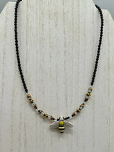 Load image into Gallery viewer, This beautiful Bee Pendant With Black and Yellow Beaded Necklace is the perfect accessory for any summer outfit. The vibrant colors will make a bold statement, while the black and gold blend adds a subtle elegance. Its perfect for any nature lover, hippie, or witchy style.   Measurements:   Necklace is 18”
