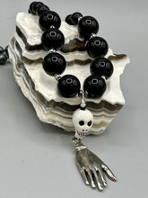 Load image into Gallery viewer, This elegant Peruvian ceramic skull beaded necklace is the perfect accessory for your unique look. With a large skull bead and a lucky hand charm, it exudes a dark, alluring vibe. Complemented with black glass and hematite stone beads, it will make a bold statement. Measurements:  Necklace: 19” in length - skulls with lucky hand charm is 2 3/4” Height
