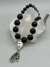 Load image into Gallery viewer, This elegant Peruvian ceramic skull beaded necklace is the perfect accessory for your unique look. With a large skull bead and a lucky hand charm, it exudes a dark, alluring vibe. Complemented with black glass and hematite stone beads, it will make a bold statement. Measurements:  Necklace: 19” in length - skulls with lucky hand charm is 2 3/4” Height

