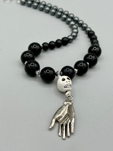 This elegant Peruvian ceramic skull beaded necklace is the perfect accessory for your unique look. With a large skull bead and a lucky hand charm, it exudes a dark, alluring vibe. Complemented with black glass and hematite stone beads, it will make a bold statement. Measurements:  Necklace: 19” in length - skulls with lucky hand charm is 2 3/4” Height