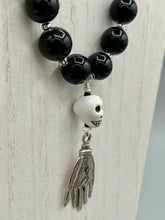 Load image into Gallery viewer, This elegant Peruvian ceramic skull beaded necklace is the perfect accessory for your unique look. With a large skull bead and a lucky hand charm, it exudes a dark, alluring vibe. Complemented with black glass and hematite stone beads, it will make a bold statement. Measurements:  Necklace: 19” in length - skulls with lucky hand charm is 2 3/4” Height

