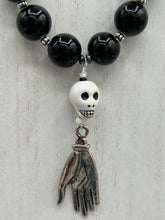 Load image into Gallery viewer, This elegant Peruvian ceramic skull beaded necklace is the perfect accessory for your unique look. With a large skull bead and a lucky hand charm, it exudes a dark, alluring vibe. Complemented with black glass and hematite stone beads, it will make a bold statement. Measurements:  Necklace: 19” in length - skulls with lucky hand charm is 2 3/4” Height
