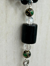 Load image into Gallery viewer, This elegant black obsidian square-shaped beaded necklace is the perfect accessory for your unique look. With a large black bead adorned with multi-color cloisonné bead and a lucky hand charm, it exudes a dark, alluring vibe. Complemented with black glass and hematite stone beads, it will make a bold statement.  Measurements:  Necklace: 18” in length - lucky hand charm is 3 1 /2” Height
