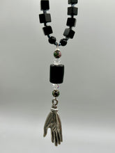 Load image into Gallery viewer, This elegant black obsidian square-shaped beaded necklace is the perfect accessory for your unique look. With a large black bead adorned with multi-color cloisonné bead and a lucky hand charm, it exudes a dark, alluring vibe. Complemented with black glass and hematite stone beads, it will make a bold statement.  Measurements:  Necklace: 18” in length - lucky hand charm is 3 1 /2” Height
