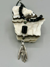 Load image into Gallery viewer, This elegant black obsidian square-shaped beaded necklace is the perfect accessory for your unique look. With a large black bead adorned with multi-color cloisonné bead and a lucky hand charm, it exudes a dark, alluring vibe. Complemented with black glass and hematite stone beads, it will make a bold statement.  Measurements:  Necklace: 18” in length - lucky hand charm is 3 1 /2” Height
