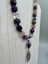 Load image into Gallery viewer, This nature-inspired accessory features an array of unique hues, including rainbow fluorite stone beads and iridescent dark shimmery purple glass beads with hints of gold, blue, pink, and green. The secure hook-eye clasp makes it perfect for day to night wear, allowing you to add a touch of summer to your wardrobe. The necklace is further complemented by a large square-shaped rainbow fluorite bead and a lucky hand charm. Measurements:  Necklace: 18&quot;, Lucky hand pendant 3&quot;

