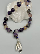 Load image into Gallery viewer, This nature-inspired accessory features an array of unique hues, including rainbow fluorite stone beads and iridescent dark shimmery purple glass beads with hints of gold, blue, pink, and green. The secure hook-eye clasp makes it perfect for day to night wear, allowing you to add a touch of summer to your wardrobe. The necklace is further complemented by a large square-shaped rainbow fluorite bead and a lucky hand charm. Measurements:  Necklace: 18&quot;, Lucky hand pendant 3&quot;
