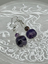 Load image into Gallery viewer, This luxurious set of earrings feature large square-shaped rainbow fluorite beads contrasted against round amethyst beads, presenting an elegant neutral yet cool-toned look. With its unique and versatile style, these earrings make a perfect addition to any wardrobe.  Measurements: 1 3/8” in length
