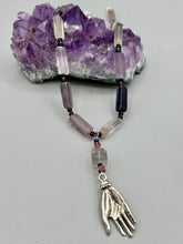 Load image into Gallery viewer, This nature-inspired accessory features an array of unique hues, including rectangular-shaped rainbow fluorite stone beads, round amethyst beads and dark purple glass beads. The secure hook-eye clasp makes it perfect for day to night wear, allowing you to add a touch of summer to your wardrobe. The necklace is further complemented by a large square-shaped rainbow fluorite bead and a lucky hand charm.  Measurements:  Necklace: 18&quot;, Lucky hand pendant 3&quot;
