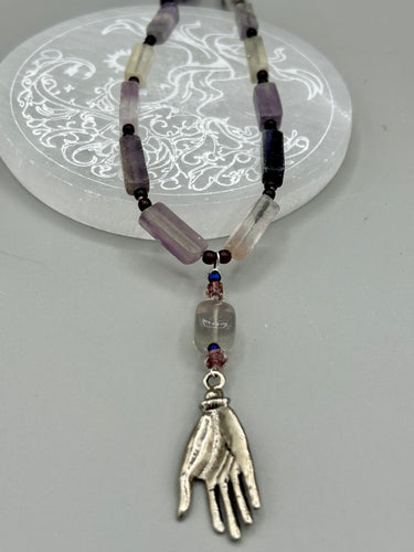 This nature-inspired accessory features an array of unique hues, including rectangular-shaped rainbow fluorite stone beads, round amethyst beads and dark purple glass beads. The secure hook-eye clasp makes it perfect for day to night wear, allowing you to add a touch of summer to your wardrobe. The necklace is further complemented by a large square-shaped rainbow fluorite bead and a lucky hand charm.  Measurements:  Necklace: 18