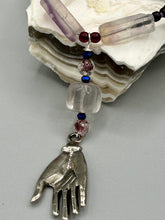 Load image into Gallery viewer, This nature-inspired accessory features an array of unique hues, including rectangular-shaped rainbow fluorite stone beads, round amethyst beads and dark purple glass beads. The secure hook-eye clasp makes it perfect for day to night wear, allowing you to add a touch of summer to your wardrobe. The necklace is further complemented by a large square-shaped rainbow fluorite bead and a lucky hand charm.  Measurements:  Necklace: 18&quot;, Lucky hand pendant 3&quot;
