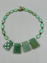 Load image into Gallery viewer, This expertly crafted necklace features a large trapezoid-shaped green aventurine stone, mint green melon beads with gold shimmer, and teal glass beads with an amber tone. Intricately arranged together, this piece offers genuine stones and an elegant bohemian style.  Measurements:  Necklace is 19&quot;
