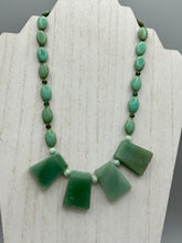 Load image into Gallery viewer, This expertly crafted necklace features a large trapezoid-shaped green aventurine stone, mint green melon beads with gold shimmer, and teal glass beads with an amber tone. Intricately arranged together, this piece offers genuine stones and an elegant bohemian style.  Measurements:  Necklace is 19&quot;
