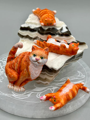 Cat lovers dream, this hand-crafted orange tabby cat magnet art is the purrfect decoration on refrigerators, lockers, cubicles or toolboxes. The set includes three mini cat figurines, featuring emerald green eyes.  Measurements: H 2” x W 1/2” x D 3/8” - Cat Magnet  H 2” x W 3/8” x D 3/8” -   Cat Figurines