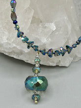 Load image into Gallery viewer, Make a bold statement with this shimmery aqua blue and blue tones glass beaded necklace. The round faceted shaped pendant compliments the cool tones of the necklace, perfect for adding a rich pop of color to any Spring outfit. The draped design gives this piece an elegant, bohemian look.  Measurements:    Necklace is 18” in length, pendant is 1 1/2”
