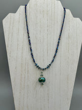 Load image into Gallery viewer, Make a bold statement with this shimmery aqua blue and blue tones glass beaded necklace. The round faceted shaped pendant compliments the cool tones of the necklace, perfect for adding a rich pop of color to any Spring outfit. The draped design gives this piece an elegant, bohemian look.  Measurements:    Necklace is 18” in length, pendant is 1 1/2”
