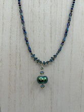 Load image into Gallery viewer, Make a bold statement with this shimmery aqua blue and blue tones glass beaded necklace. The round faceted shaped pendant compliments the cool tones of the necklace, perfect for adding a rich pop of color to any Spring outfit. The draped design gives this piece an elegant, bohemian look.  Measurements:    Necklace is 18” in length, pendant is 1 1/2”
