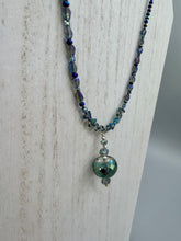 Load image into Gallery viewer, Make a bold statement with this shimmery aqua blue and blue tones glass beaded necklace. The round faceted shaped pendant compliments the cool tones of the necklace, perfect for adding a rich pop of color to any Spring outfit. The draped design gives this piece an elegant, bohemian look.  Measurements:    Necklace is 18” in length, pendant is 1 1/2”
