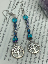 Load image into Gallery viewer, This captivating set of earrings boasts an exquisite range of intense blues and purples, accented with a warm touch of gold and green. The dangling silver plated tree of life charm adds a beautiful finishing touch.  Measurements: 2 1/2” in length
