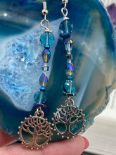 Load image into Gallery viewer, This captivating set of earrings boasts an exquisite range of intense blues and purples, accented with a warm touch of gold and green. The dangling silver plated tree of life charm adds a beautiful finishing touch.  Measurements: 2 1/2” in length
