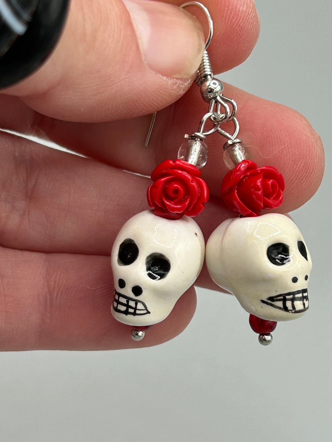 Peruvian off white ceramic skull beads come with quartzite red rose beads. These stylish skull earrings are perfect for adding a unique flair to any outfit. Whether you're looking for a Dia De Los Muertos accessory or simply looking to draw inspiration, these goth pieces perfectly capture the vampire goth, witchy, dark, Chingona Cabrona, Latina Chicana styles.  Measurements: 1” in length