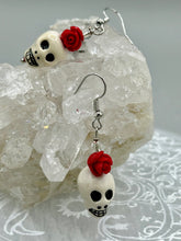 Load image into Gallery viewer, Peruvian off white ceramic skull beads come with quartzite red rose beads. These stylish skull earrings are perfect for adding a unique flair to any outfit. Whether you&#39;re looking for a Dia De Los Muertos accessory or simply looking to draw inspiration, these goth pieces perfectly capture the vampire goth, witchy, dark, Chingona Cabrona, Latina Chicana styles.  Measurements: 1” in length
