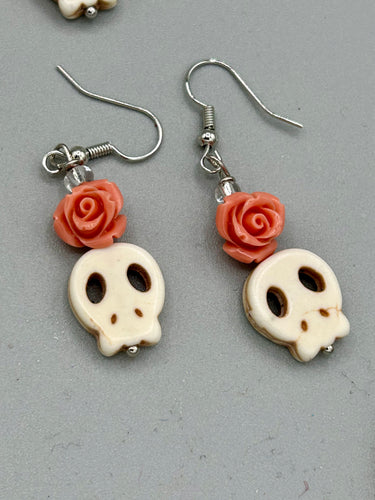 These stylish skull earrings are perfect for adding a unique flair to any outfit. Whether you're looking for a Dia De Los Muertos accessory or simply looking to draw inspiration, these goth pieces perfectly capture the vampire goth, witchy, dark, Chingona Cabrona, Latina Chicana styles. Crafted with Howlite stone skull beads and peachy coral quartzize floral beaded earrings, this jewelry set is a unique stunning statement piece.  Measurements: 1 1/4 ” in length