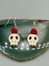 Load image into Gallery viewer, These stylish skull earrings are perfect for adding a unique flair to any outfit. Whether you&#39;re looking for a Dia De Los Muertos accessory or simply looking to draw inspiration, these goth pieces perfectly capture the vampire goth, witchy, dark, Chingona Cabrona, Latina Chicana styles. Howlite stone skull bead with red quartzize floral beads.  Measurements: 1 1/4 ” in length
