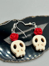 Load image into Gallery viewer, These stylish skull earrings are perfect for adding a unique flair to any outfit. Whether you&#39;re looking for a Dia De Los Muertos accessory or simply looking to draw inspiration, these goth pieces perfectly capture the vampire goth, witchy, dark, Chingona Cabrona, Latina Chicana styles. Howlite stone skull bead with red quartzize floral beads.  Measurements: 1 1/4 ” in length
