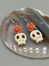 Load image into Gallery viewer, These stylish skull earrings are perfect for adding a unique flair to any outfit. Whether you&#39;re looking for a Dia De Los Muertos accessory or simply looking to draw inspiration, these goth pieces perfectly capture the vampire goth, witchy, dark, Chingona Cabrona, Latina Chicana styles. Crafted with Howlite stone skull beads and peachy coral quartzize floral beaded earrings, this jewelry set is a unique stunning statement piece.  Measurements: 1 1/4 ” in length
